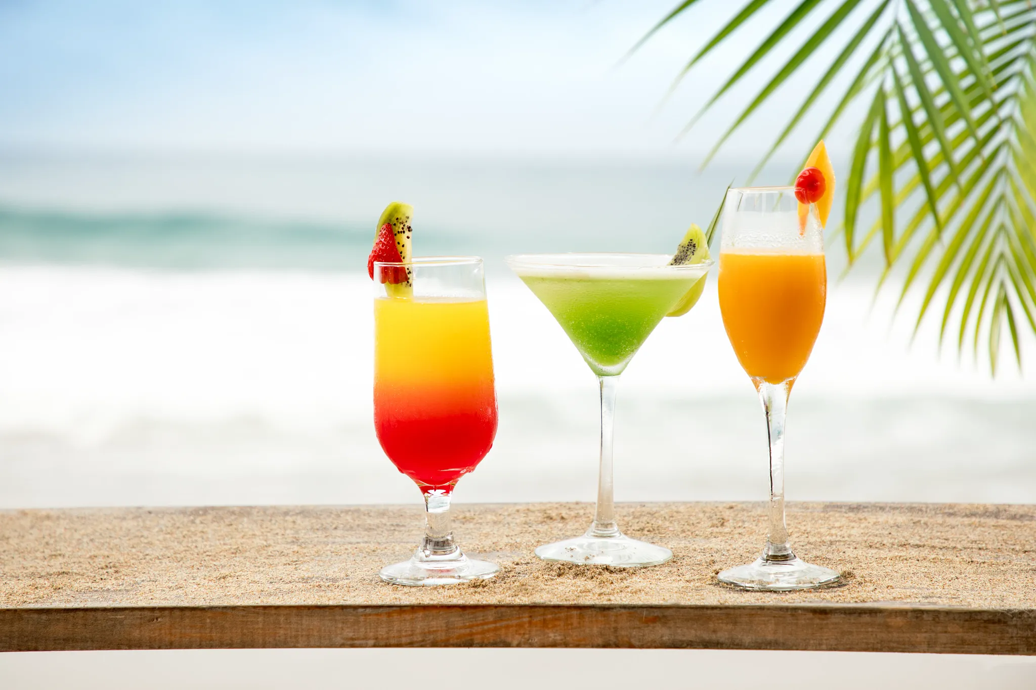 Colorful tropical cocktails served at Barracuda Pool & Beach Bar at Secrets Playa Mujeres Golf & Spa Resort with ocean views and fresh fruit garnishes.